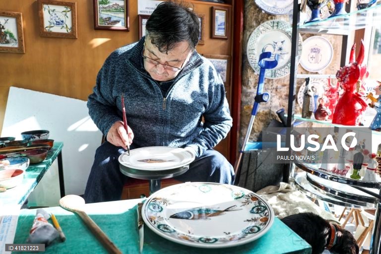 O artesão Carlos Tomás pinta um prato de louça tradicional "ratinho" na sua loja no largo da Sé Velha, em Coimbra, 31 de outubro de 2023. O artesão de Coimbra reclama aos 69 anos o lugar de último pintor de louça 'ratinho', ligada aos antigos movimentos migratórios dos camponeses do Centro e do Norte para os trabalhos agrícolas sazonais do Sul. (ACOMPANHA TEXTO DA LUSA DO DIA 11 DE NOVEMBRO DE 2023). PAULO NOVAIS/LUSA