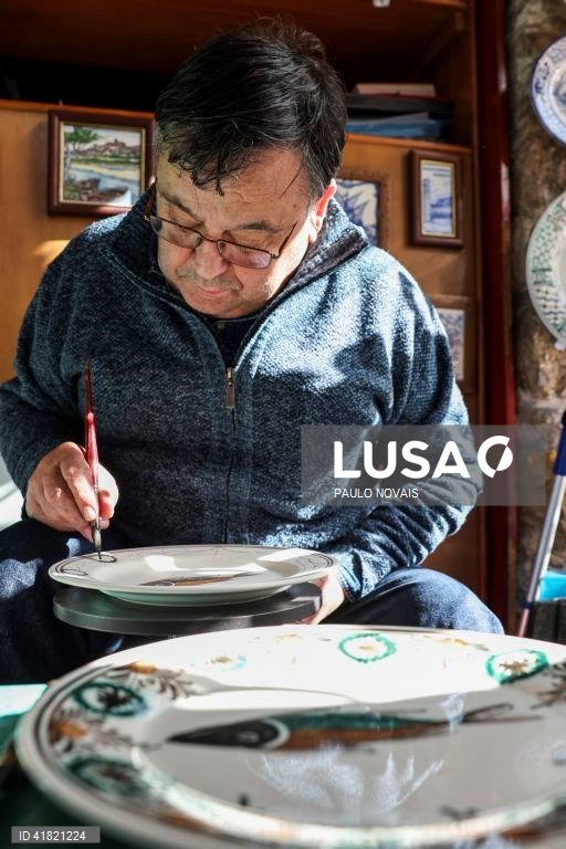 O artesão Carlos Tomás pinta um prato de louça tradicional "ratinho" na sua loja no largo da Sé Velha, em Coimbra, 31 de outubro de 2023. O artesão de Coimbra reclama aos 69 anos o lugar de último pintor de louça 'ratinho', ligada aos antigos movimentos migratórios dos camponeses do Centro e do Norte para os trabalhos agrícolas sazonais do Sul. (ACOMPANHA TEXTO DA LUSA DO DIA 11 DE NOVEMBRO DE 2023). PAULO NOVAIS/LUSA