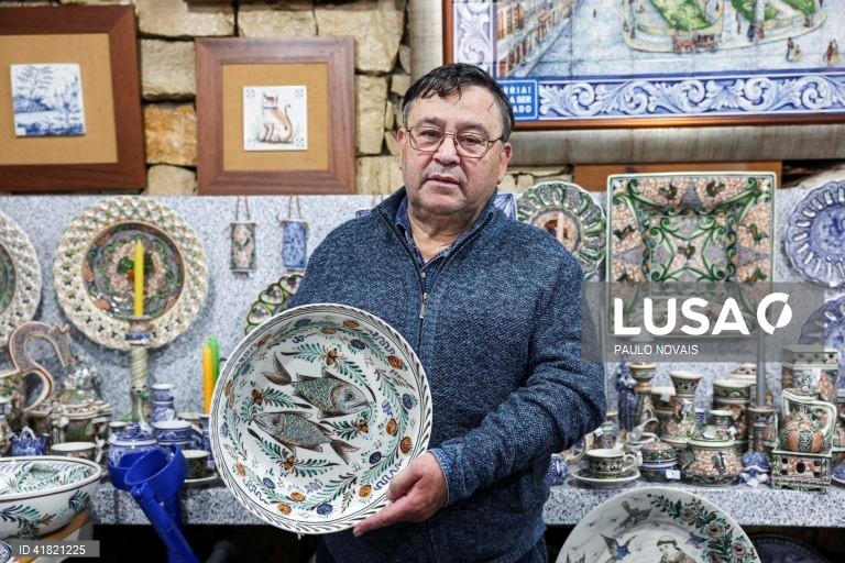O artesão Carlos Tomás exibe prato de louça tradicional "ratinho" pintado à mão na sua loja no largo da Sé Velha, em Coimbra, 31 de outubro de 2023. O artesão de Coimbra reclama aos 69 anos o lugar de último pintor de louça 'ratinho', ligada aos antigos movimentos migratórios dos camponeses do Centro e do Norte para os trabalhos agrícolas sazonais do Sul. (ACOMPANHA TEXTO DA LUSA DO DIA 11 DE NOVEMBRO DE 2023). PAULO NOVAIS/LUSA