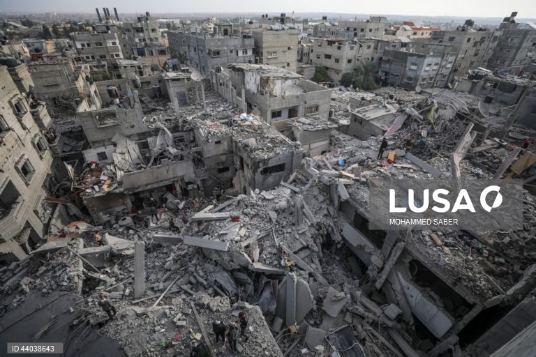 Palestinianos inspeccionam os escombros de edifícios destruídos na sequência de ataques aéreos israelitas no campo de refugiados de Al Nuseirat, no centro da Faixa de Gaza.