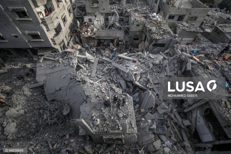 Palestinianos inspeccionam os escombros de edifícios destruídos na sequência de ataques aéreos israelitas no campo de refugiados de Al Nuseirat, no centro da Faixa de Gaza.