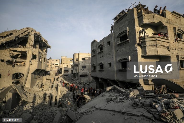 Palestinianos inspeccionam os escombros de edifícios destruídos na sequência de ataques aéreos israelitas no campo de refugiados de Al Nuseirat, no centro da Faixa de Gaza.