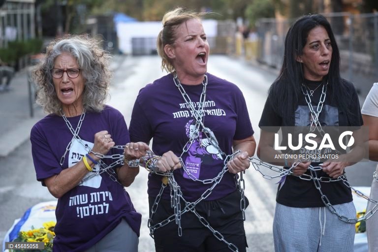 Mães de reféns e soldados israelitas participam num protesto em frente à casa do primeiro-ministro Benjamin Netanyahu, acorrentando-se e transportando três caixões vazios, em Jerusalém, Israel, 18 de setembro de 2025. Os três caixões simbolizam o próximo refém que será assassinado devido à pressão militar, o segundo para o seguinte refém falecido devido aos bombardeamentos das Forças de Defesa de Israel (IDF) e o terceiro para o próximo soldado que morrerá na "guerra sem sentido" em Gaza....