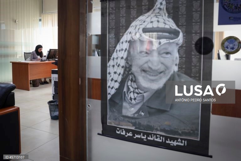 Uma mulher trabalha num escritório ao lado da imagem do antigo líder da Autoridade Palestiniana, Yasser Arafat, na cidade de Ramallah, Cisjordânia, 23 de setembro de 2025. ANTÓNIO PEDRO SANTOS/LUSA

