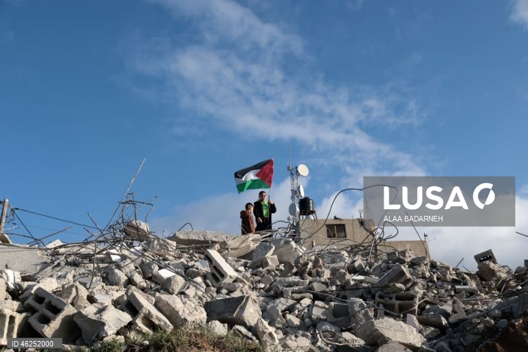 Um menino palestiniano agita uma bandeira palestiniana sobre os escombros da casa pertencente à família de Malik Ismail Salem na aldeia de Bizarya, perto da cidade de Nablus, na Cisjordânia. O exército israelita demoliu a casa de Malik Ismail Salem, que foi morto por tiros israelitas em 10 de julho de 2025, de acordo com a agência de notícias palestiniana WAFA.