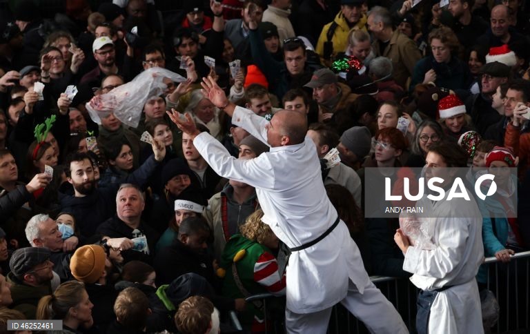 Pessoas observam enquanto talhantes distribuem carne no leilão de carne de Natal em Smithfield, Londres, Grã-Bretanha. Centenas de pessoas reunem-se para ter a oportunidade de comprar carne a preços promocionais na véspera de Natal no mercado de Smithfield, em Londres.