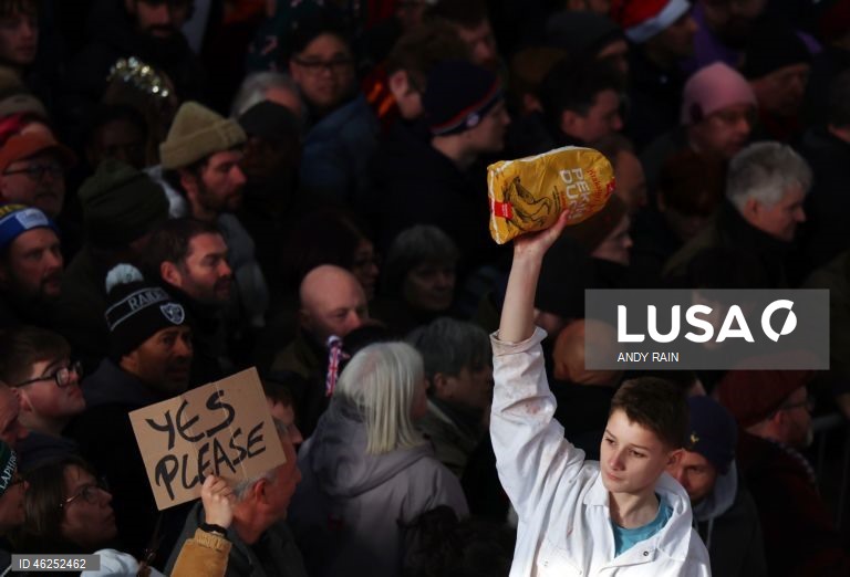 Pessoas observam enquanto talhantes distribuem carne no leilão de carne de Natal em Smithfield, Londres, Grã-Bretanha. Centenas de pessoas reunem-se para ter a oportunidade de comprar carne a preços promocionais na véspera de Natal no mercado de Smithfield, em Londres.