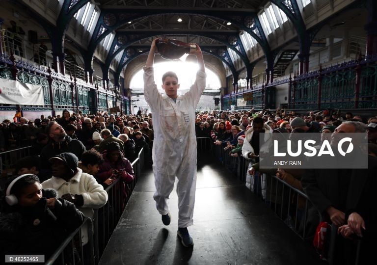 Pessoas observam enquanto talhantes distribuem carne no leilão de carne de Natal em Smithfield, Londres, Grã-Bretanha. Centenas de pessoas reunem-se para ter a oportunidade de comprar carne a preços promocionais na véspera de Natal no mercado de Smithfield, em Londres.