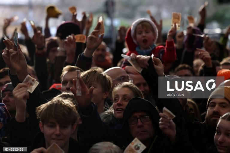 Pessoas observam enquanto talhantes distribuem carne no leilão de carne de Natal em Smithfield, Londres, Grã-Bretanha. Centenas de pessoas reunem-se para ter a oportunidade de comprar carne a preços promocionais na véspera de Natal no mercado de Smithfield, em Londres.