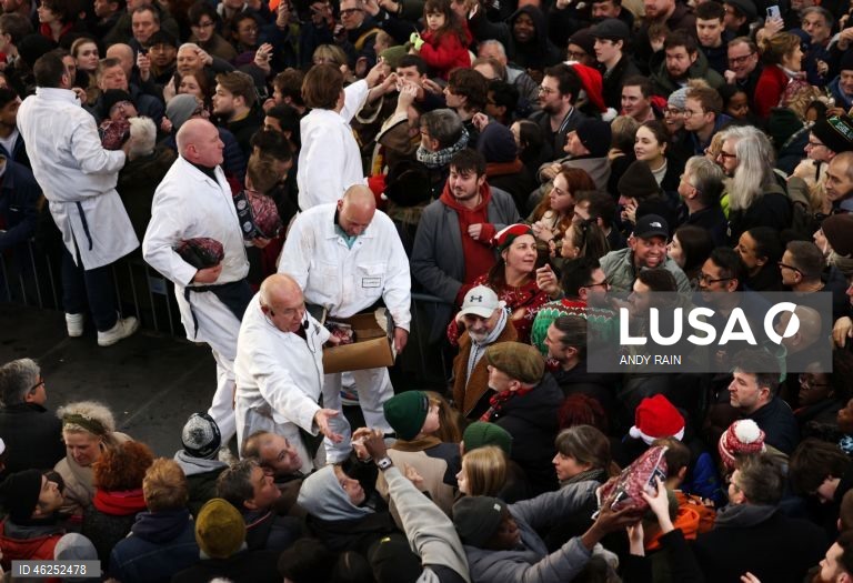 Pessoas observam enquanto talhantes distribuem carne no leilão de carne de Natal em Smithfield, Londres, Grã-Bretanha. Centenas de pessoas reunem-se para ter a oportunidade de comprar carne a preços promocionais na véspera de Natal no mercado de Smithfield, em Londres.
