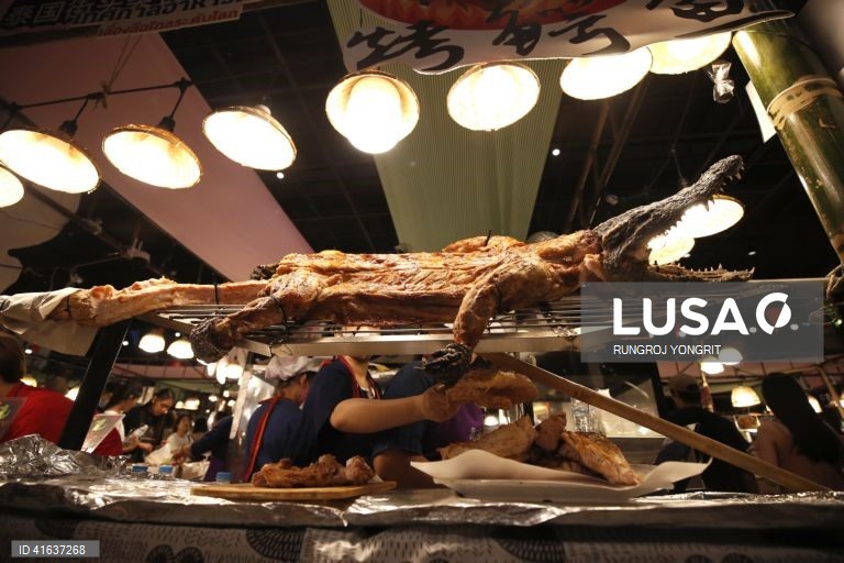 Vendedores de comida tailandesa vendem carne de crocodilo grelhada no mercado de rua em Banguecoque, Tailândia. A carne de crocodilo tem sido considerada uma carne nutricional altamente saudável, com menos gordura, baixo teor de colesterol e maior teor de proteínas do que a carne de porco ou de frango, com benefícios para a saúde do coração e para a circulação sanguínea.