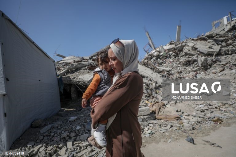 Palestinianos deslocados passam pelos escombros de edifícios destruídos no campo de refugiados de Jabalia, no norte da Faixa de Gaza, depois de o exército israelita ter emitido ordens de evacuação para as zonas do norte e do leste da Faixa de Gaza.