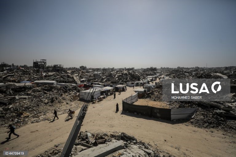 Palestinianos deslocados passam pelos escombros de edifícios destruídos no campo de refugiados de Jabalia, no norte da Faixa de Gaza, depois de o exército israelita ter emitido ordens de evacuação para as zonas do norte e do leste da Faixa de Gaza.