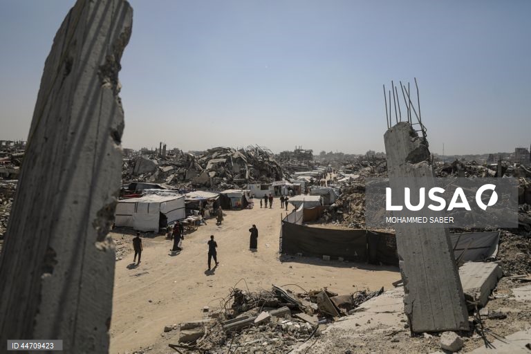 Palestinianos deslocados passam pelos escombros de edifícios destruídos no campo de refugiados de Jabalia, no norte da Faixa de Gaza, depois de o exército israelita ter emitido ordens de evacuação para as zonas do norte e do leste da Faixa de Gaza.