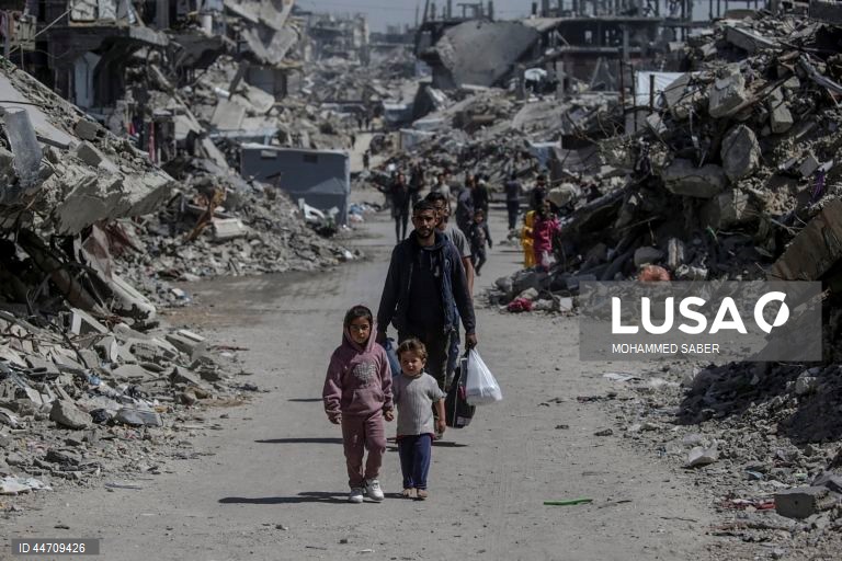 Palestinianos deslocados passam pelos escombros de edifícios destruídos no campo de refugiados de Jabalia, no norte da Faixa de Gaza, depois de o exército israelita ter emitido ordens de evacuação para as zonas do norte e do leste da Faixa de Gaza.