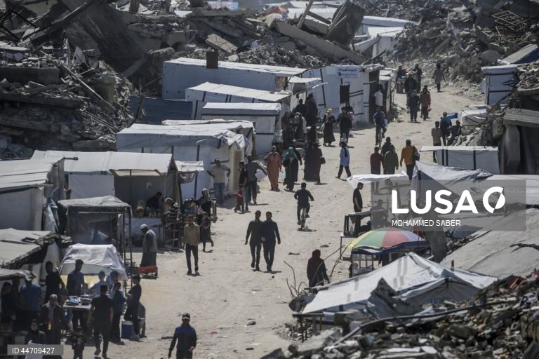 Palestinianos deslocados passam pelos escombros de edifícios destruídos no campo de refugiados de Jabalia, no norte da Faixa de Gaza, depois de o exército israelita ter emitido ordens de evacuação para as zonas do norte e do leste da Faixa de Gaza.