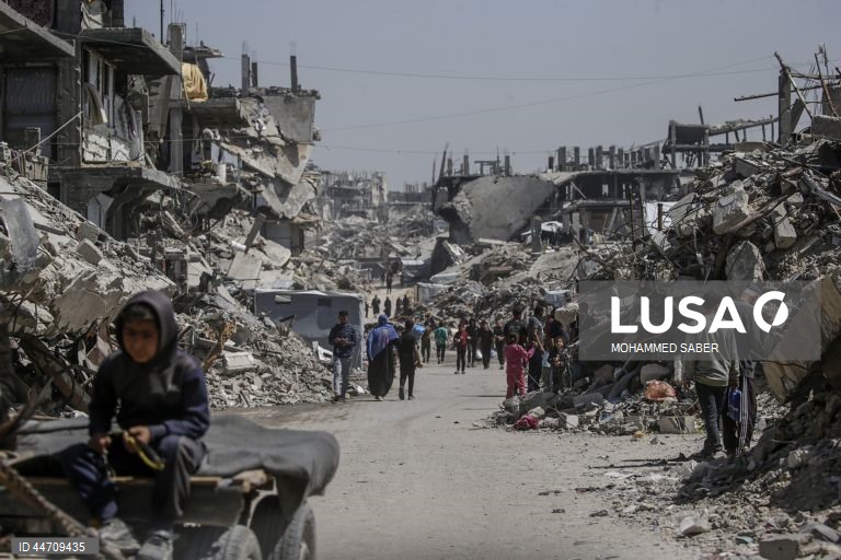 Palestinianos deslocados passam pelos escombros de edifícios destruídos no campo de refugiados de Jabalia, no norte da Faixa de Gaza, depois de o exército israelita ter emitido ordens de evacuação para as zonas do norte e do leste da Faixa de Gaza.