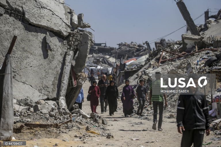 Palestinianos deslocados passam pelos escombros de edifícios destruídos no campo de refugiados de Jabalia, no norte da Faixa de Gaza, depois de o exército israelita ter emitido ordens de evacuação para as zonas do norte e do leste da Faixa de Gaza.