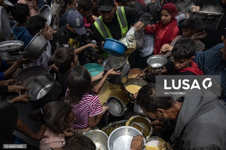 Palestinianos deslocados recolhem alimentos doados em Jabalia, no norte de Gaza