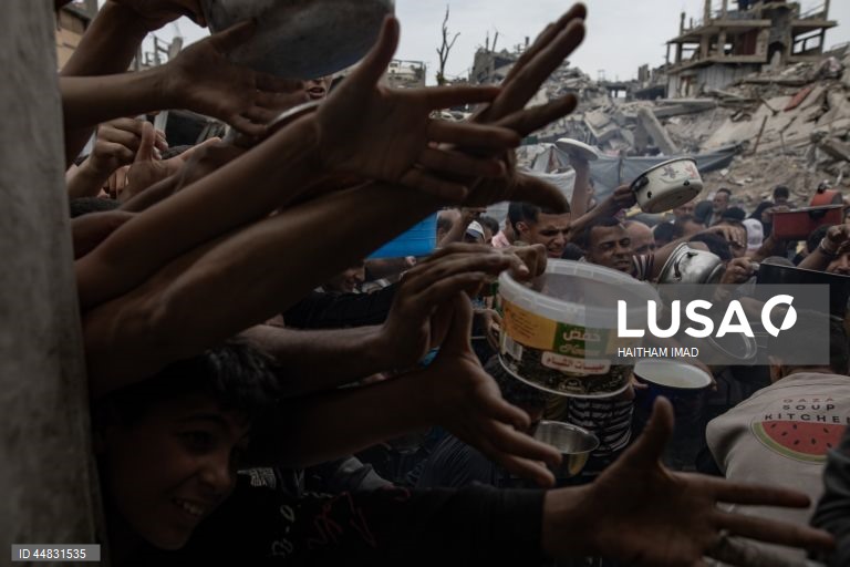 Palestinianos deslocados recolhem alimentos doados em Jabalia, no norte de Gaza