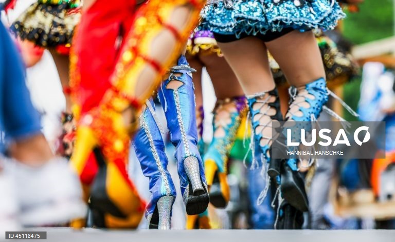 Pessoas vestem trajes tradicionais enquanto participam no Carnaval das Culturas em Berlim, Alemanha. O desfile envolve mais de 4 000 participantes que exibem as culturas dos seus países de origem. O Carnaval das Culturas é celebrado anualmente em Berlim desde 1996 e pretende ser um símbolo da diversidade e da coexistência pacífica. 