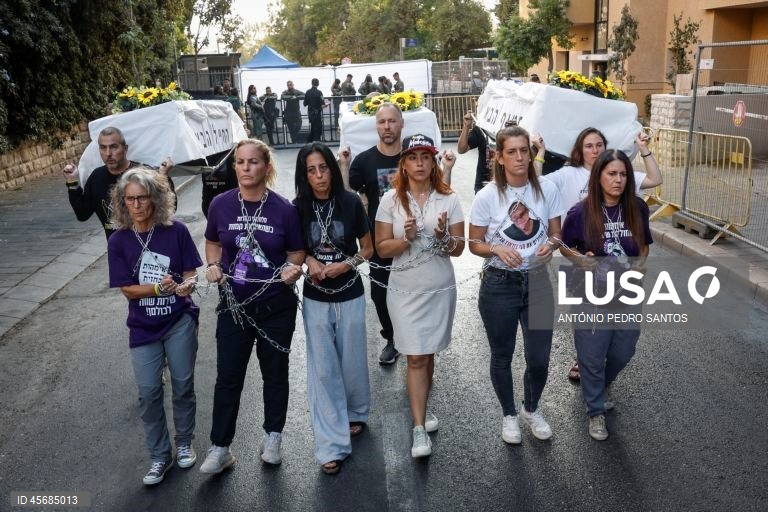 Mães de reféns e soldados israelitas participam num protesto em frente à casa do primeiro-ministro Benjamin Netanyahu, acorrentando-se e transportando três caixões vazios, em Jerusalém, Israel, 18 de setembro de 2025. Os três caixões simbolizam o próximo refém que será assassinado devido à pressão militar, o segundo para o seguinte refém falecido devido aos bombardeamentos das Forças de Defesa de Israel (IDF) e o terceiro para o próximo soldado que morrerá na "guerra sem sentido" em Gaza....