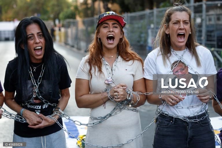 Mães de reféns e soldados israelitas participam num protesto em frente à casa do primeiro-ministro Benjamin Netanyahu, acorrentando-se e transportando três caixões vazios, em Jerusalém, Israel, 18 de setembro de 2025. Os três caixões simbolizam o próximo refém que será assassinado devido à pressão militar, o segundo para o seguinte refém falecido devido aos bombardeamentos das Forças de Defesa de Israel (IDF) e o terceiro para o próximo soldado que morrerá na "guerra sem sentido" em Gaza....